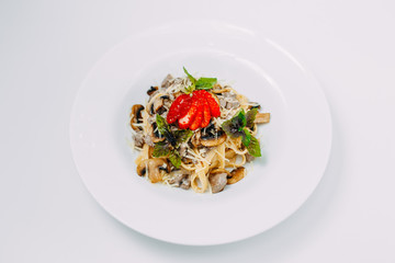 Italian pasta in a creamy sauce with mushrooms champignon on a white plate