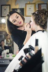 master class makeup training, takes place in the studio where the students are sitting. held on a model that sits in a wedding hairstyle and jewelry