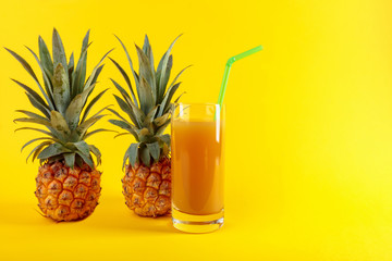 Fresh ripe pineapples and juice on a yellow background.