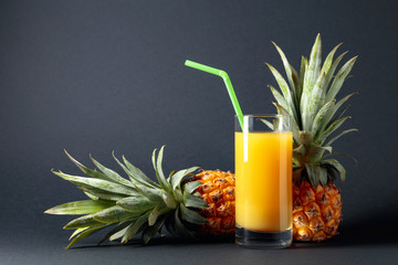 Fresh ripe pineapples and juice on a black background.
