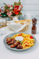 spicy chicken wings with french fries and sauce on an isolated white background