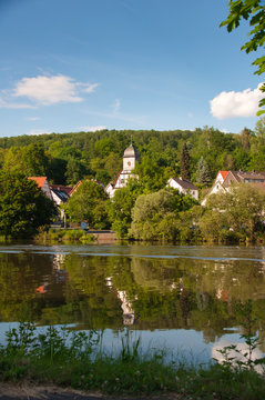 die st. marienkirche in spiekershausen an der fulda vom hotel roter kater und graue katze am gegen&uuml;ber liegenden ufer aus gesehen bei kassel hessen
