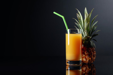 Pineapple and juice on a black reflective background.