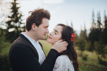 Wedding in the mountains. Young couple cuddling against the backdrop of the forest and mountains at sunset