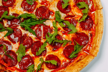 italian pizza with mozzarella and salami with arugula isolated on a white background