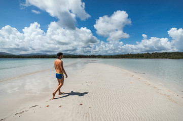 A young man takes a walk on a sand dune between two waters in a Puerto Princesa beach, Palawan, Philippines