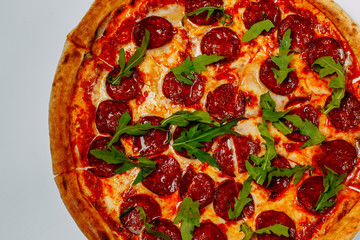 italian pizza with mozzarella and salami with arugula isolated on a white background