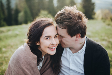 Fototapeta premium Wedding in the mountains. Young couple cuddling against the backdrop of the forest and mountains at sunset