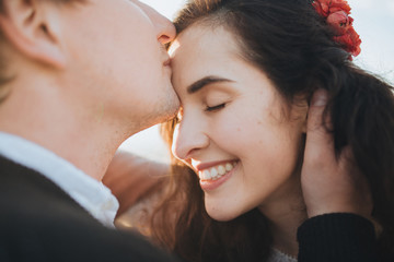 Wedding in the mountains. Young couple kisses and hugs on a background of mountains at sunset