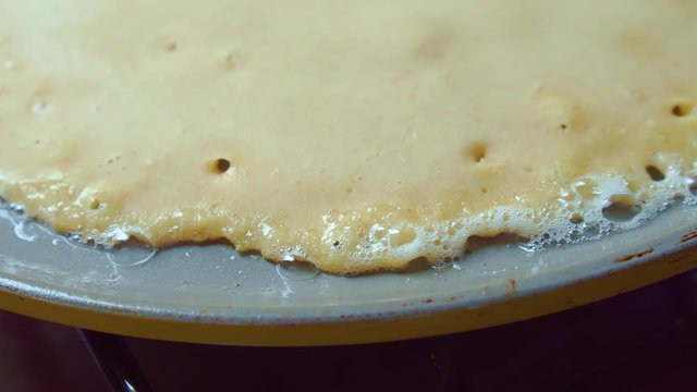 Close up of pancake fried in butter gray pan. Oil bubbles. Homemade Delicious.