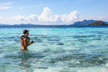 Fototapeta na wymiar A young tourist man walking inside the water in Coron, Philippines