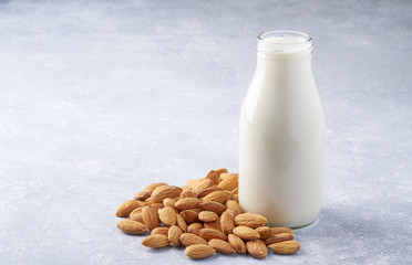 almonds and a bottle of almond milk on a light grey background. Vegan milk.