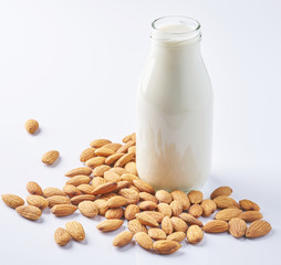 almonds and a bottle of almond milk on a white background. Vegan milk.