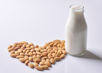 Almond milk bottle and nuts forming a heart shape  on white background