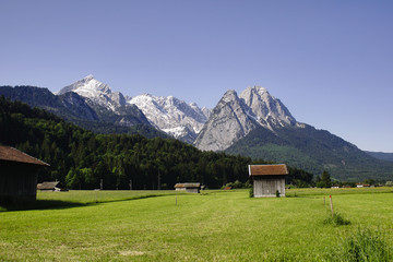 Fototapeta na wymiar Deutsche Alpengipfel in der Nähe von Garmisch-Patenkirchen mit Wiese, Wald und Hütten.