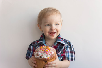 A child with an Easter cake on a white background. A cheerful little boy eats a cake. Festive mood.