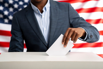 African american man holds envelope in hand above vote ballot