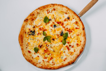 Italian pizza with different types of cheese and basil on a white background