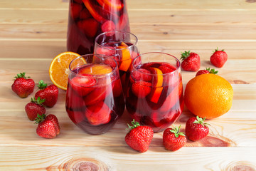 Red wine sangria with fruits in glasses and pitcher and fresh fruits near on wooden table. Selective focus .