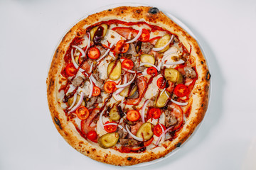 Italian pizza with cheese and beef with vegetables and tomatoes on a white background
