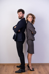 business man and woman standing shoulder to shoulder in suits on a white background, strong, vertical