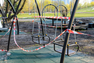 An empty playground, wrapped with a warning red and white tape, which is forbidden to visit during the quarantine period of the pandemic of COVID-19 disease caused by coronavirus