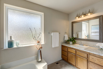 Bright rambler home bathroom interior with older style cabinets and blue accents in decor.