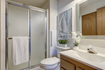 Bright rambler home bathroom interior with older style cabinets and blue accents in decor.