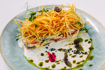 salad with french fries and sauce on a decorated white table