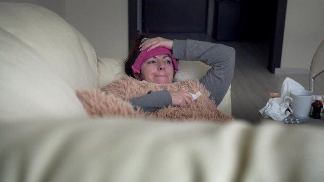 sad woman is sick alone at home is lying on the couch, cough, fever, depression