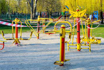An empty sport playground, whose exercisers wrapped with a warning red and white tape. Forbidden to visit during the quarantine period of the pandemic of COVID-19 disease caused by coronavirus