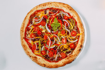 Italian pizza with cheese and beef with vegetables and tomatoes on a white background