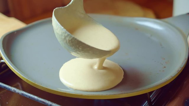 Ladle dough is poured to fry pan. Home cooking three flapjack. Slow mo