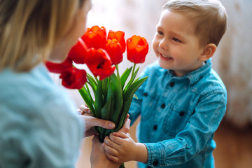 Bouquet of tulips for mom. Little son congratulates mother and gives a bouquet of flowers tulips. Happy mother's day. Family holiday and togetherness.