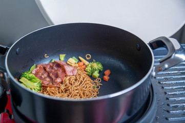 Stir-fry Instant noodles korean hot chili ramen stlye with smoke pork bacon in cooking pan.