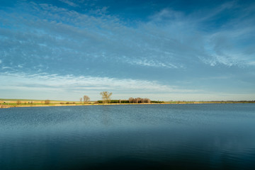Calm water surface on a lake, horizon and clouds on sky