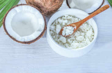 halves of a coconut, a whole coconut and a bowl of coconut paste close-up. background with fresh coconuts and coconut paste in a bowl and wooden spoon.