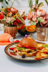 burger with beef patty and potato chips on a white decorated table