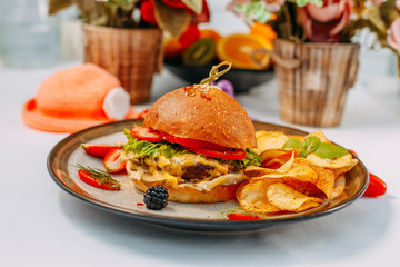 burger with beef patty and potato chips on a white decorated table