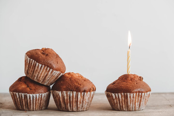 Chocolate cupcakes with candle on wooden table. Copy, empty space for text