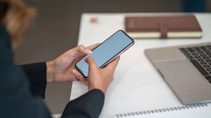 Woman sitting and holding blank screen mock up mobile phone	