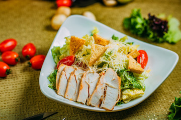 Caesar salad with chicken and vegetables on a decorated table
