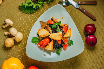 salad with eggplant and tofu and tomatoes, healthy food on a decorated table
