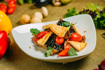 salad with eggplant and tofu and tomatoes, healthy food on a decorated table