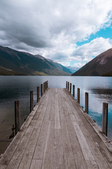 wooden pier on lake with mountains 