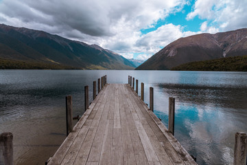 wooden pier on lake with mountains 