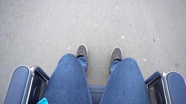 A young man is riding in a wheelchair. A disabled person moves around the city. View from above.