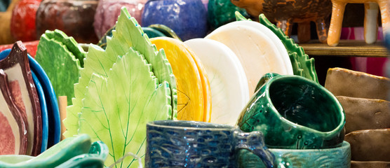 A group of bright ceramic dishes. Colored glazed pottery, cups and plates