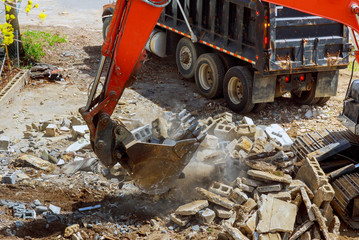Excavator loads construction waste into of material for disposal from construction