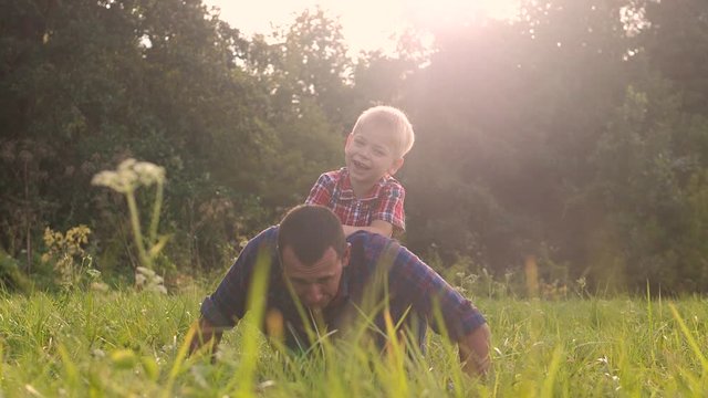 dad and son happy family play push ups lifestyle slow motion funny video . father man and son little a boy push ups in nature laugh and play